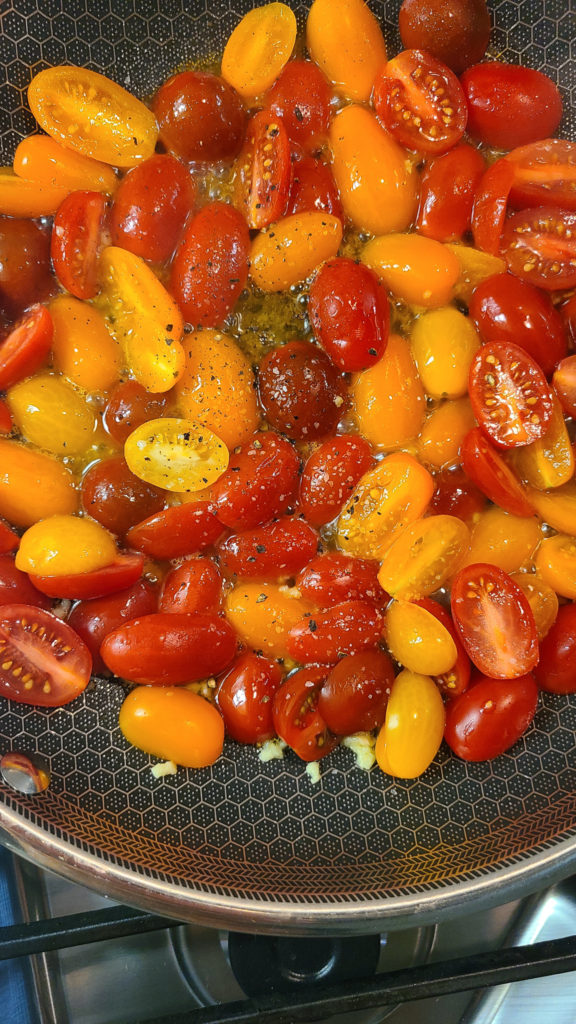 Cherry tomatoes in pan with olive oil, garlic, salt and pepper