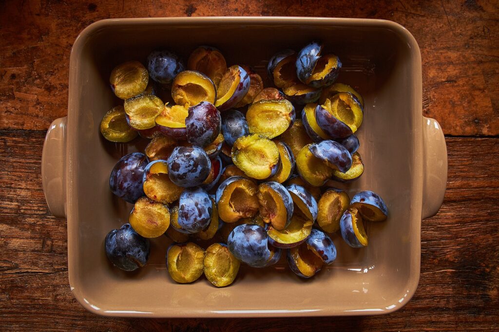 a brown food tray with fresh prunes sliced in halves